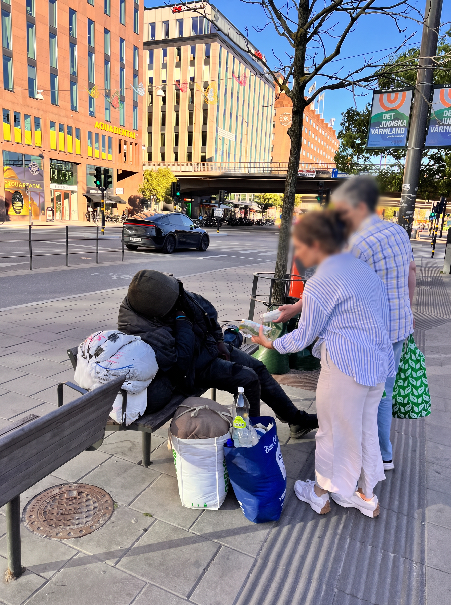 Volunteers handing food to a homeless person on a bench in Stockholm